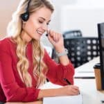 A female employee taking a customer call while writing notes.